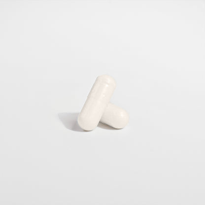 Two white Healthy8Always 5-HTP capsules stand upright on a white background, casting a soft shadow. These supplements may support serotonin levels and enhance emotional well-being.