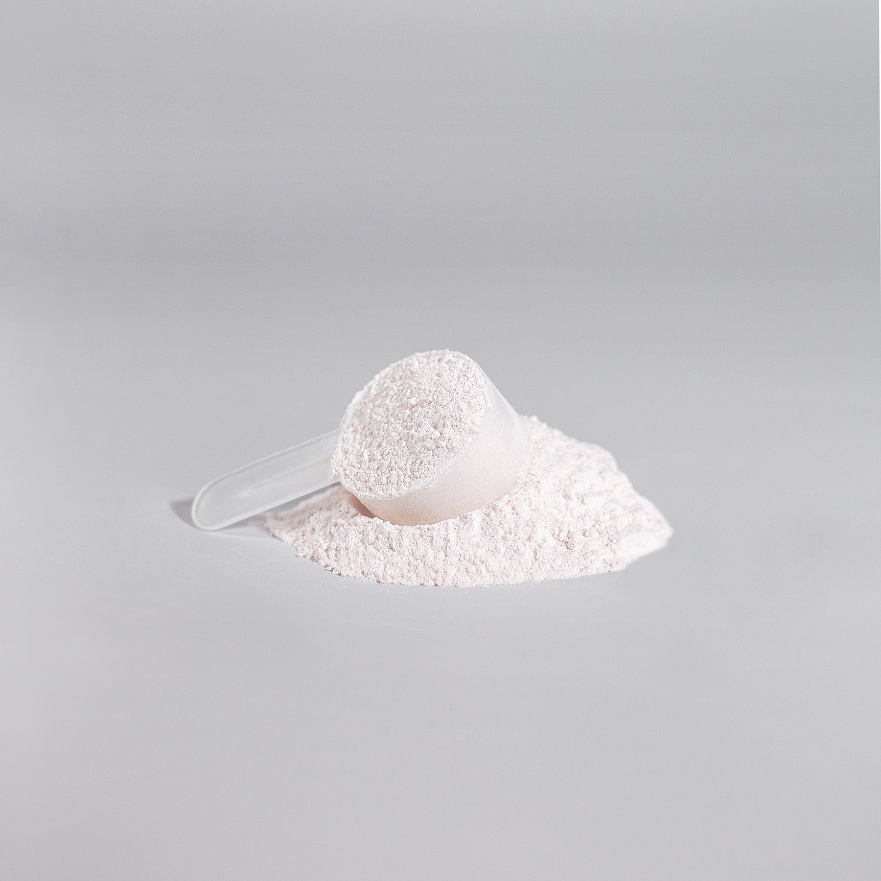 A clear scoop brimming with white powder, similar to Healthy8Always Nitric Shock Pre-Workout Powder (Fruit Punch), sits on a surface with some energy-boosting powder scattered around. The background is a plain light gray.